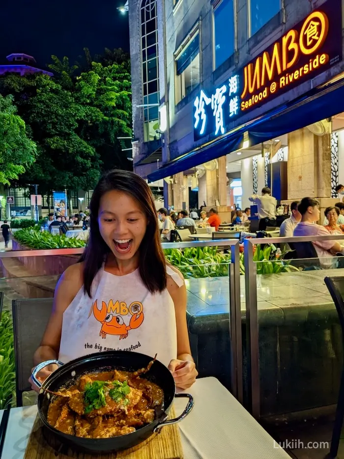 A woman holding a large pot of crab with red sauce on it.