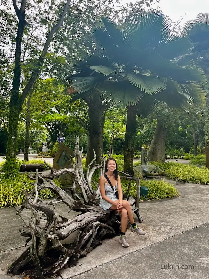 A woman sitting on a bench in a lush park.