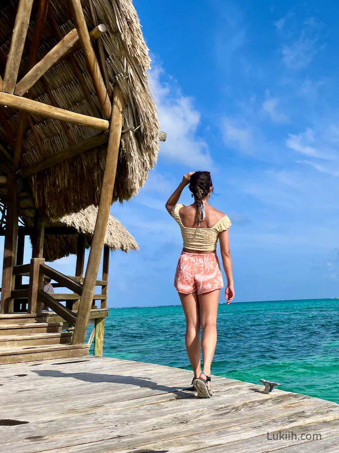 A woman standing on a swimming dock near a very blue ocean.