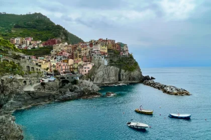 A colorful village perched on a cliff overlooking a blue ocean.