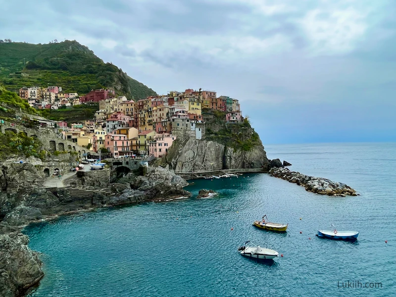 A colorful village perched on a cliff overlooking a blue ocean.