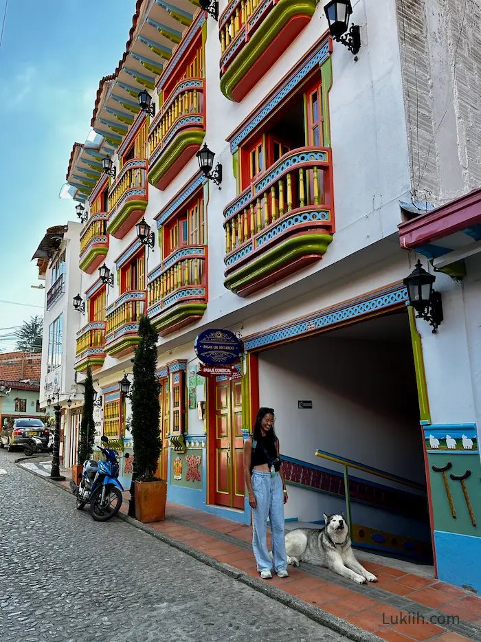 A street with a white building with colorful balconies.