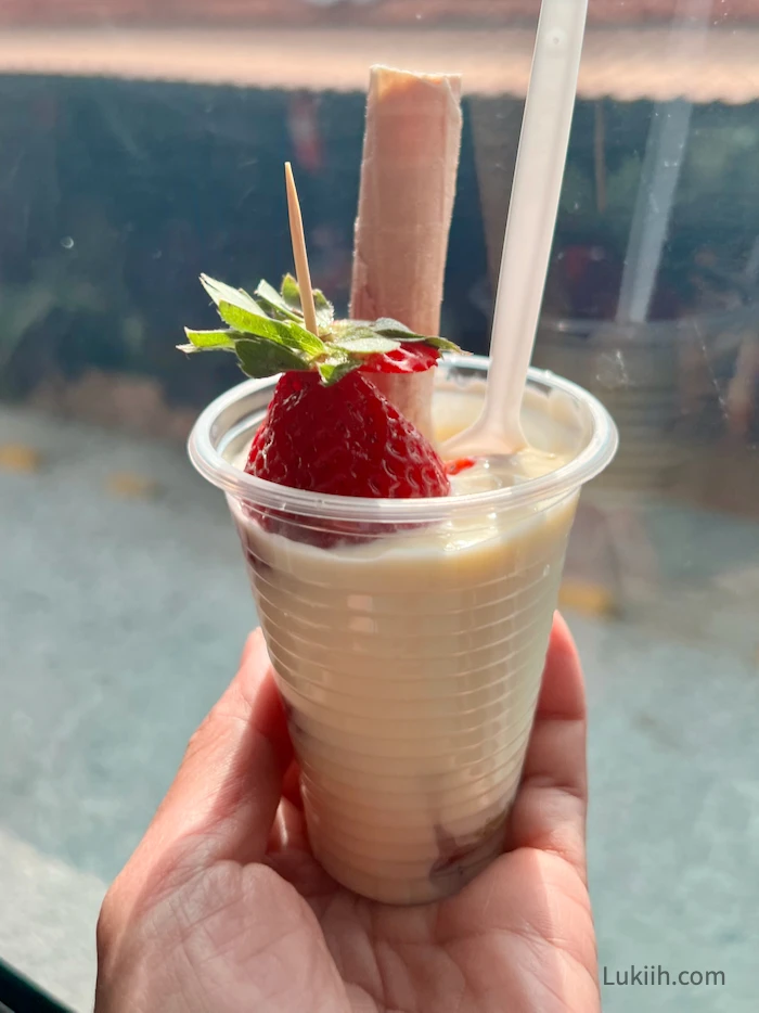 A cup holding custard and strawberries.