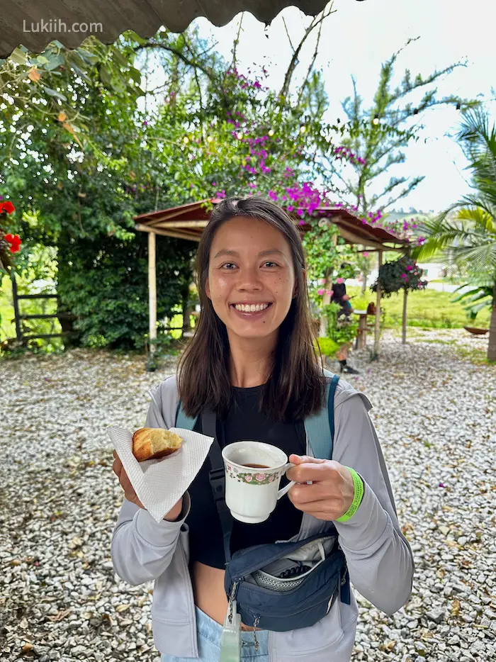 A woman holding a cup of hot chocolate with flowers in the background.