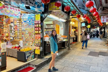 A woman walking around street markets with lantern decorations.