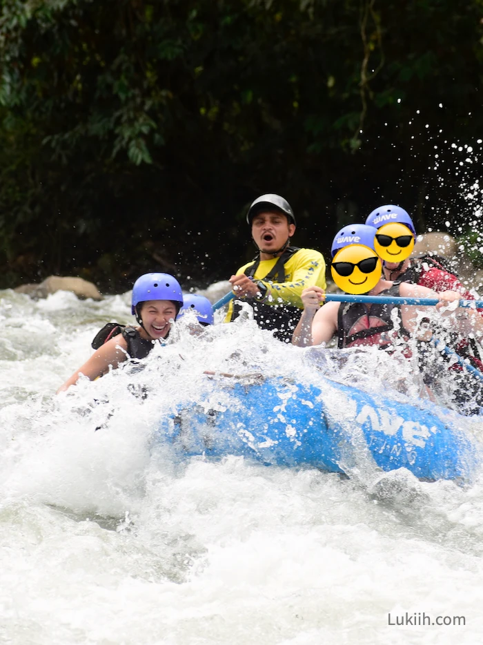 Four people riding a raft through a strong river as water splashes everywhere.