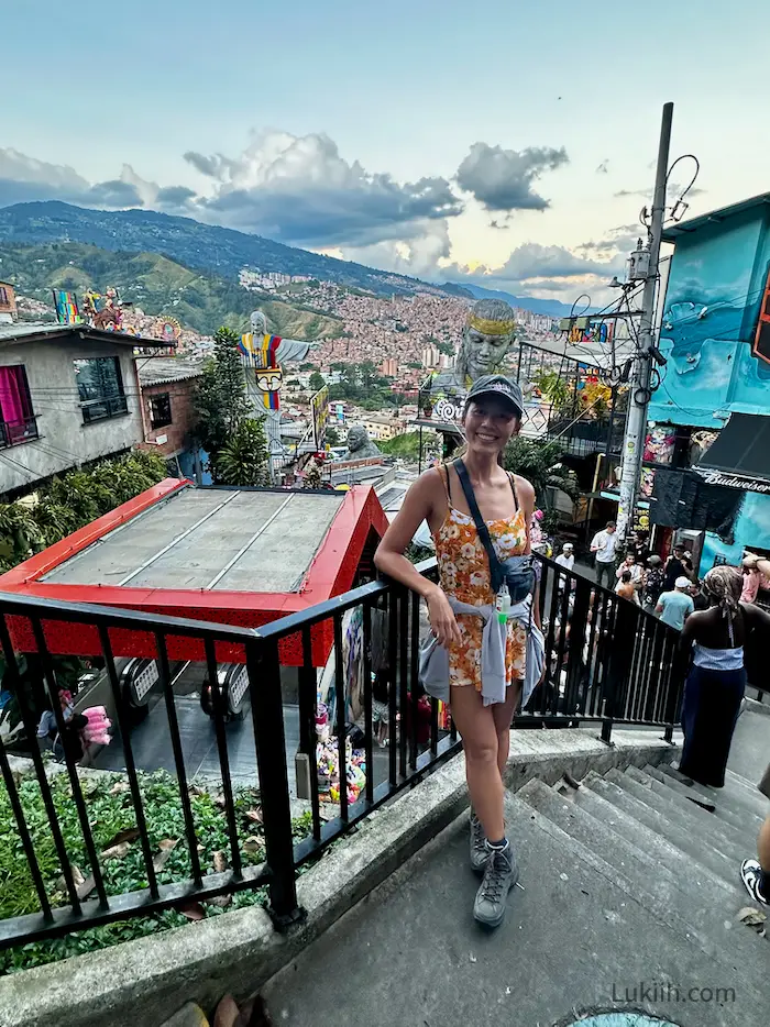 A woman standing on a set of staircases overlooking a very busy and crowded neighborhood.