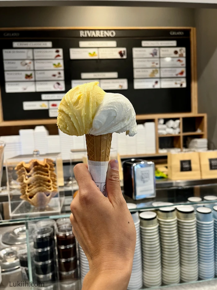 A creamy gelato with two flavors on a cone.