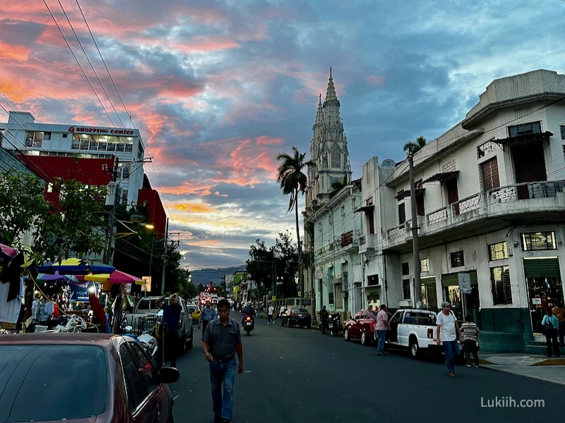 A street with an old cathedral and bustling street vendors.