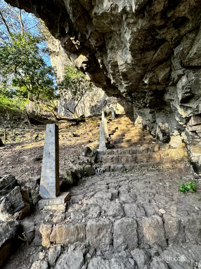 A set of stone stairs next to a large rock.