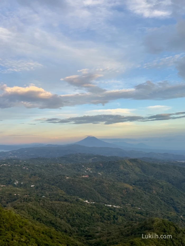 A high-up view of a lush scenery with a volcano in the background.