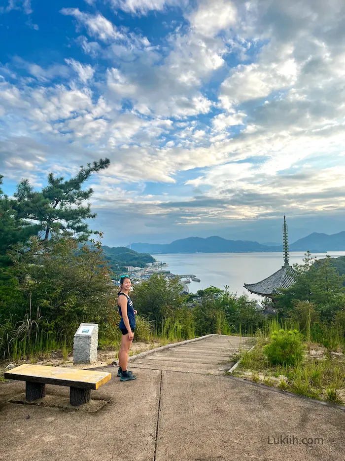 A woman standing on a hill overlooking a lake and temple.