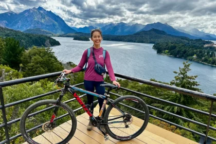 A woman with a mountain bike at a viewpoint overlooking a lake and mountain.