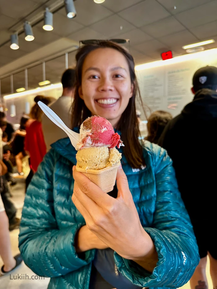 A woman holding a double-scoop ice cream.