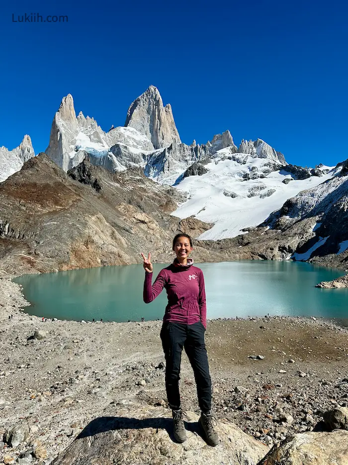 A woman standing in front of a giant rock with three peaks.