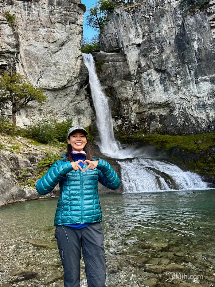 A woman posing in front of a waterfall.