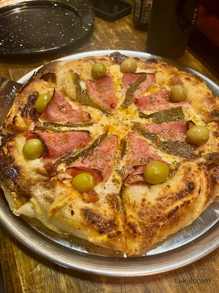 A cheesy pizza with ham and olives.