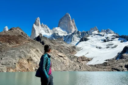 A woman looking up at a set of distinct mountain peaks.