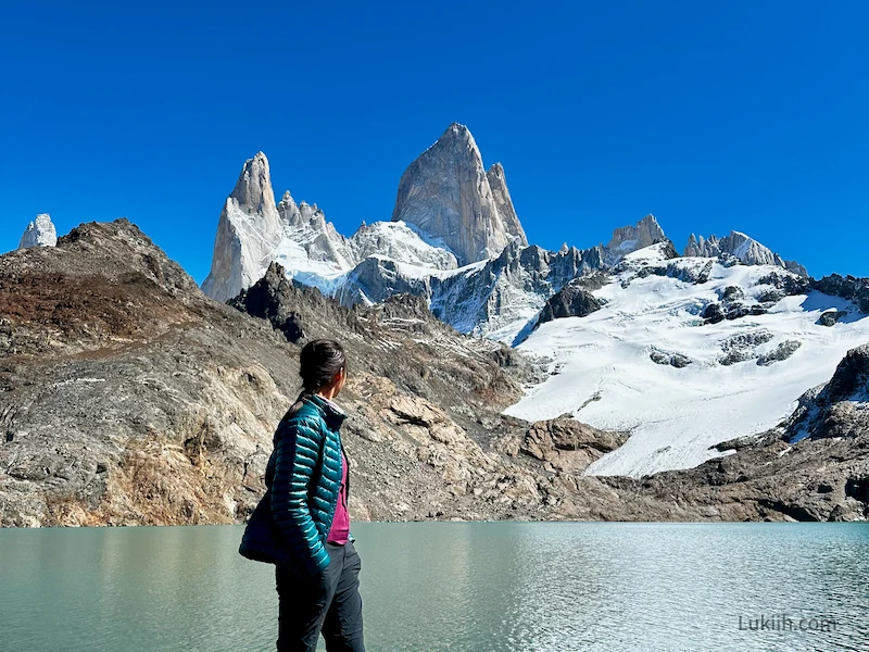 A woman looking up at a set of distinct mountain peaks.